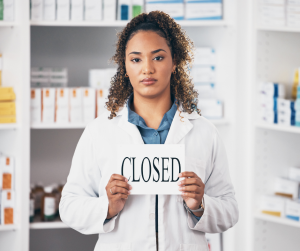 pharmacist holding a closed sign