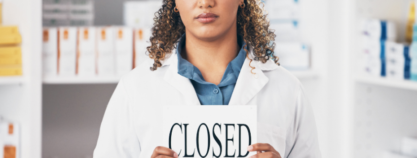 pharmacist holding a closed sign